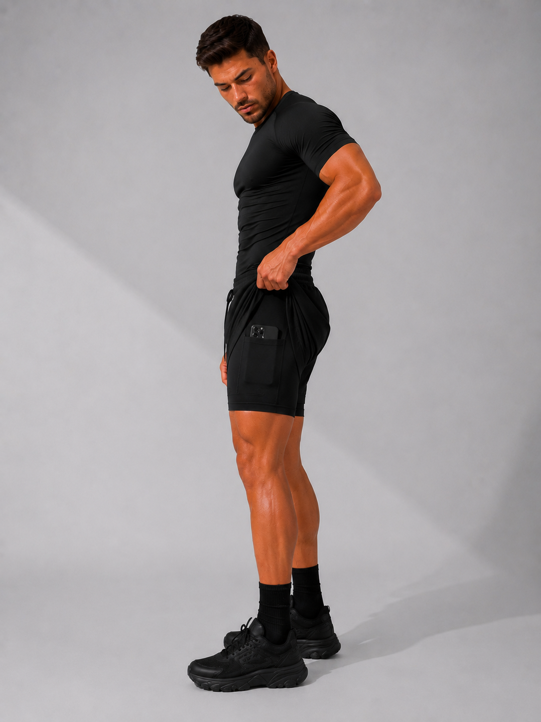 Mann trägt die 2-in-1 Performance Short in Shadow Black, Seitenansicht